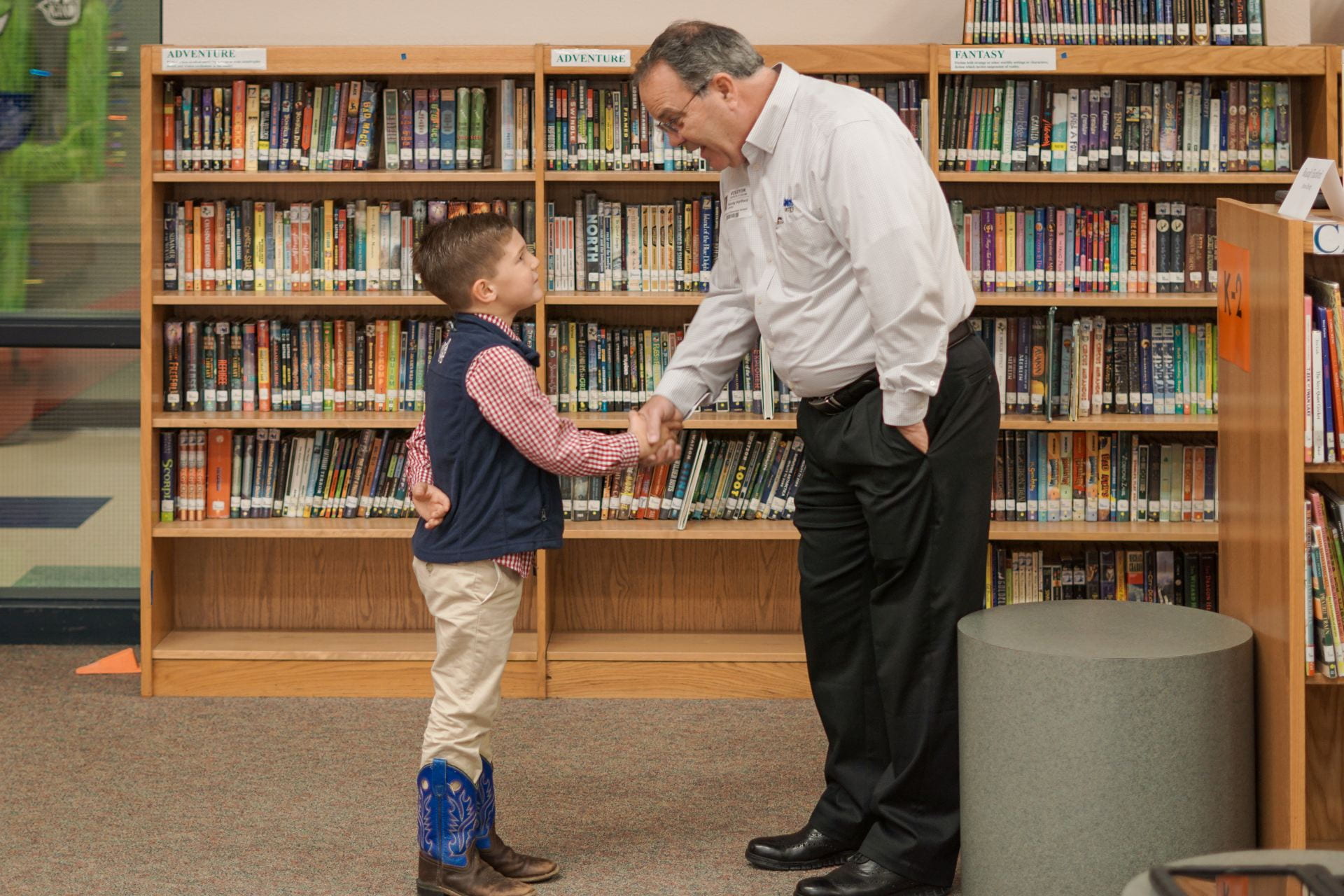Community volunteer shaking hands with a student in a library
